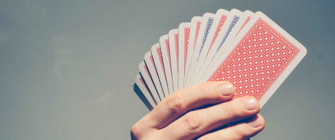 A hand holding a deck of cards, fanned out, facing away from the camera.
