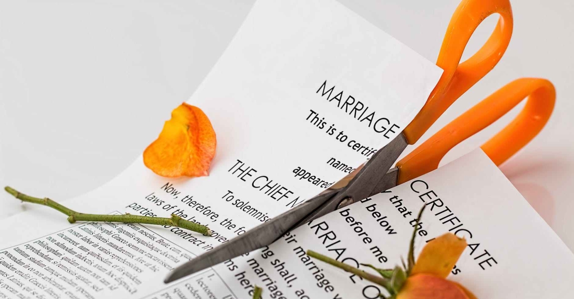 Orange scissors cutting an orange rose and a piece of paper that starts with the words "Marriage Certificate: This is to certi-fy that the .."