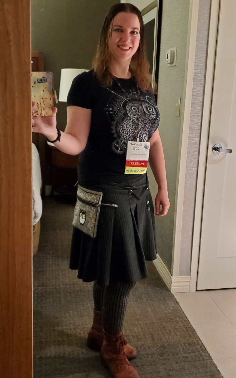 Morgan selfie, with a black steampunk owl shirt and black pinstripe skirt, and red boots.