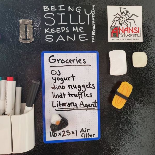 Side of a fridge.
Shopping list on a white board:
Groceries:
OJ, Yogurt, dino Nuggest, lindt truffles, Literary Agent (underlined twice), 16x25x1 Air filter.
2 magnets that look like sushi rolls. Some white board pens, a magnet that says "being silly keeps me sane the devils panties dot com.
Another magnet that says "Anansi Storytime. The Fairy tale audio drama." with a picture of a spider on it.
And a stone henge magnet.